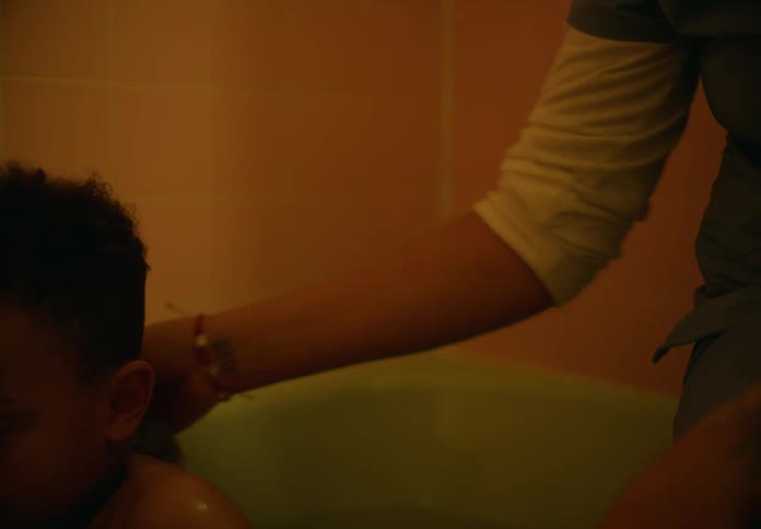 Mother scrubs the back of his son taking a bath in the bathtub at home