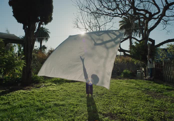Two children play outside while one is swinging and the other is playing with a sheet