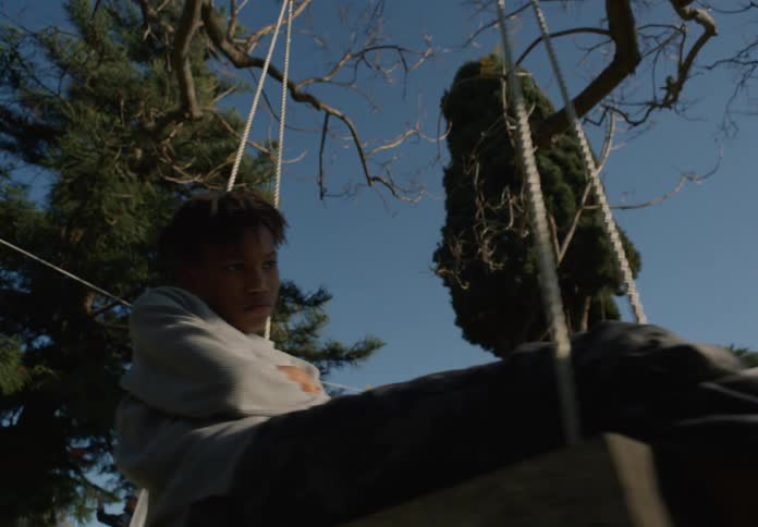 A young boy is swinging on a swing in a yard