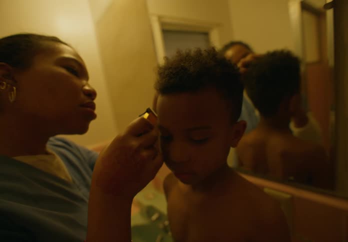 Mother trim the hairline on the temples of her son head in the bathroom