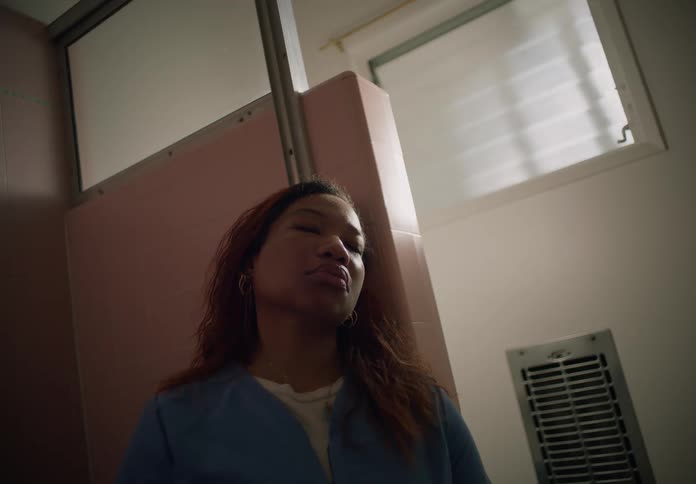 Woman leans against wall in bathroom and rests with her eyes closed