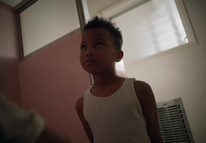 Mother touches face of her son as he stands in room with her