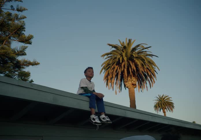 Two children are sitting on the roof and one jumps down
