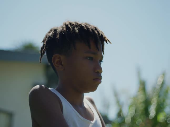 Teen boy standing outside in the yard looking at something