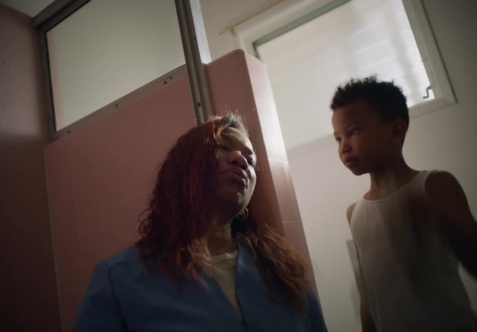 A young boy dabs at his mothers face with a cloth while caring for her in the bathroom