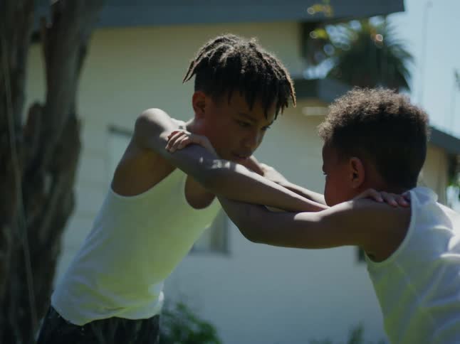 Two children wrestle in the yard
