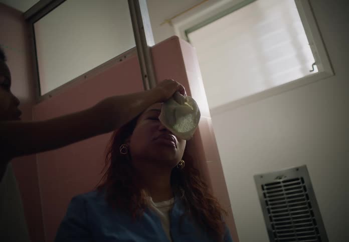 A young boy uses a wet cloth to dab the forehead of his mother