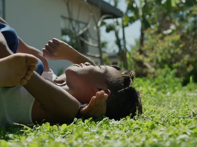 Tween brothers lying on their backs in the grass bonding and talking during the day