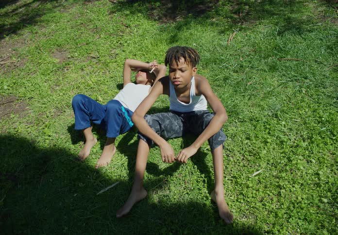 Two boys are sitting in the grass on a sunny day