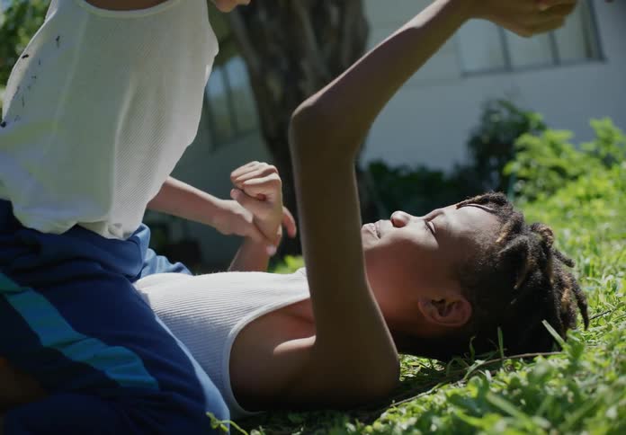 Two boys play wrestle on the grass