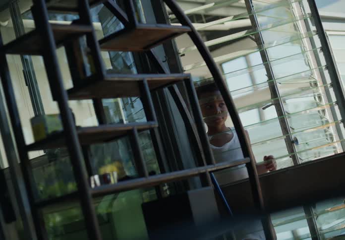 Two young boys walk up to a window and stare into it while outside the house