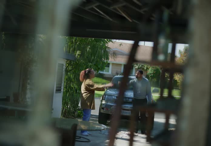 A man and woman argue with each other in the driveway of their home