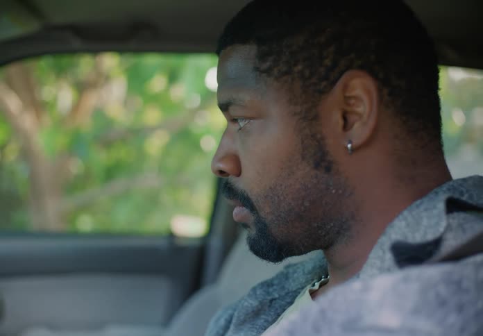A man is sitting in the driver seat of an automobile getting anxious as he waits