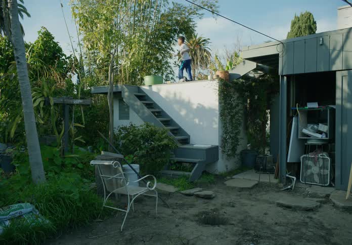 Tween boy in back yard playing coming down from roof during the day