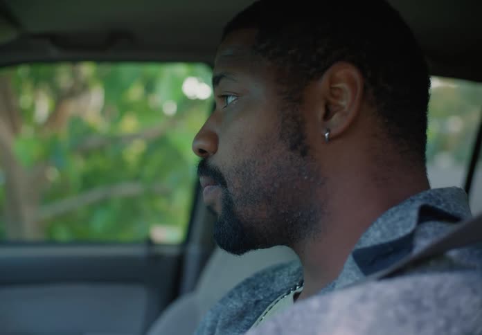 A man is sitting in the driver seat of an automobile getting anxious as he waits