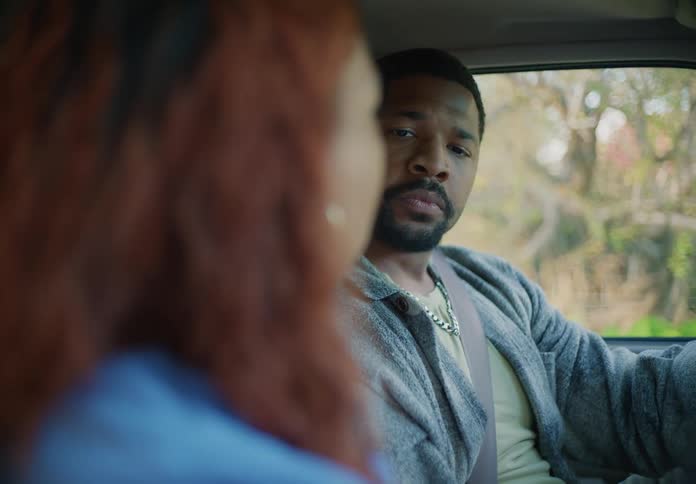 Young couple sitting on a car look at each other silently after an argument