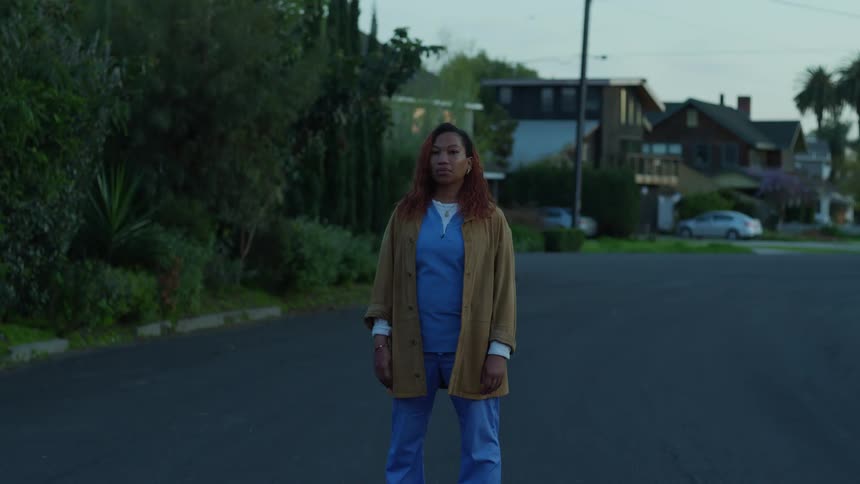 A woman is standing outdoors in a neighborhood