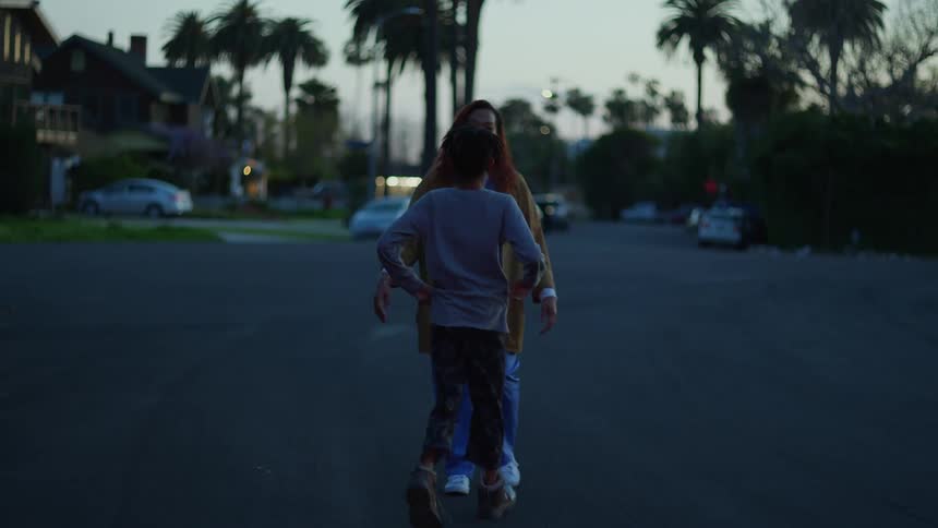 A young boy runs happily towards his mother who is walking in the street