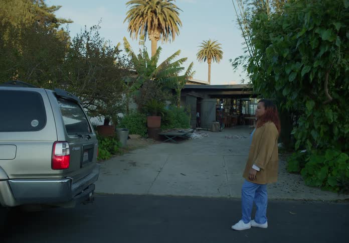 A woman standing outdoors watching a car drive off