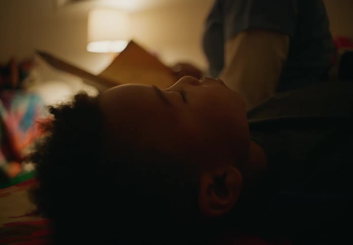 Mother reads book to children lying in bed at night