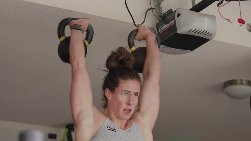 Woman lifts hand weights during workout in garage gym