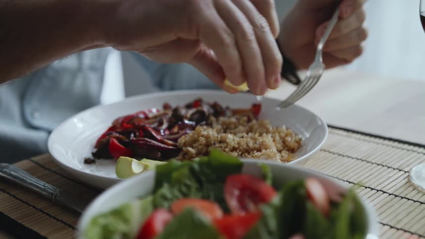 Squeezing juice from slice of lemon on meal