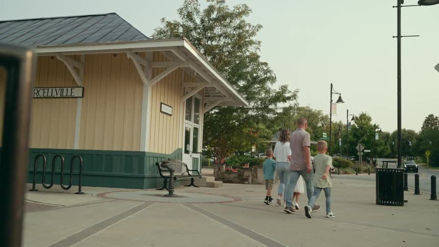 A family walks together outdoors while holding hands