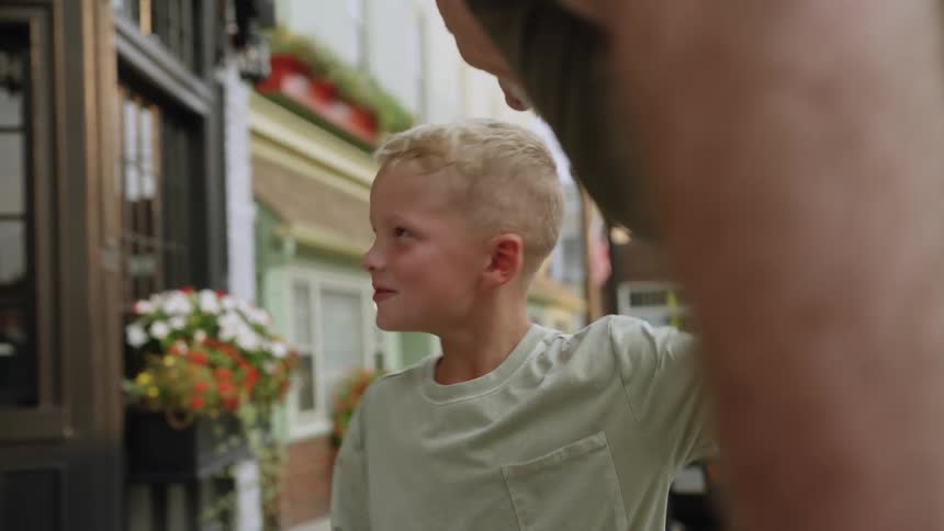 Little boy and grandpa laughing and talking outside of some shops pointing at the flowers during the day