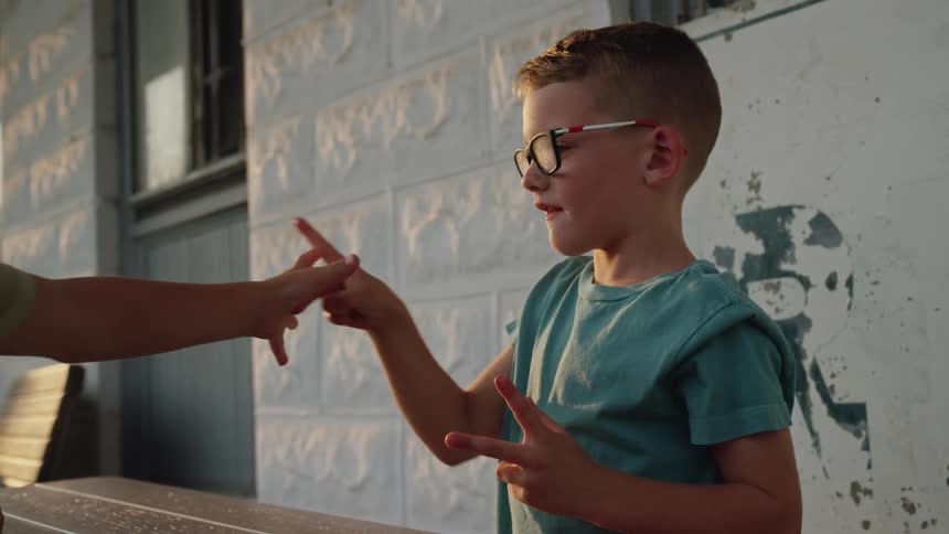 Two young boys are outside playing rock paper scissors hand game