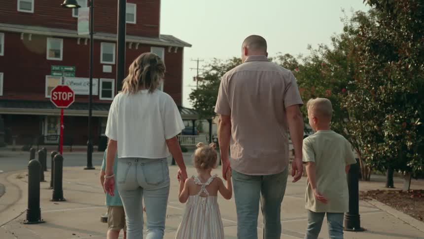 A family of a father mother two sons and a daughter walk along their suburban neighbohood toward a road with a stop sign
