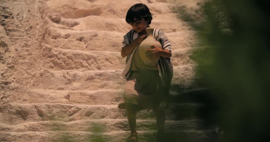 A child races down the steps with a jug