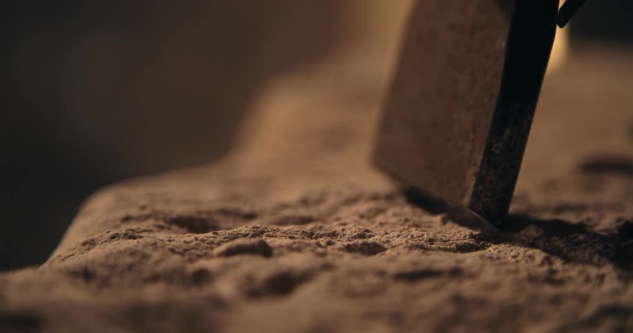 A stone being hammered on on a pile of dust