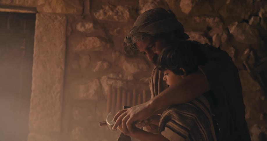 Traditional middle east stonemason teaches his son how to carve a rock with hammer and chisel