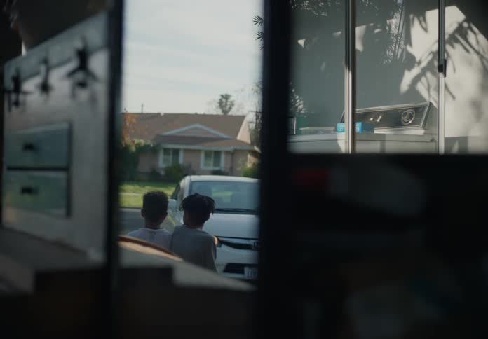 Two young boys get a hug from their mother before she drives away in her car
