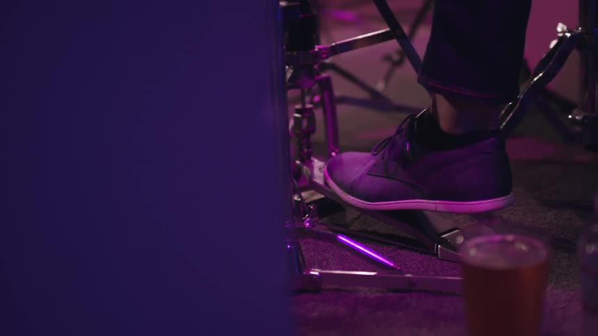 A drummer's foot bounces up and down on a drum pedal