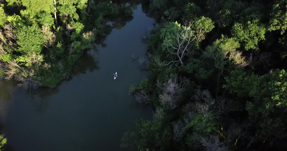 A person paddles a kayak down a stream