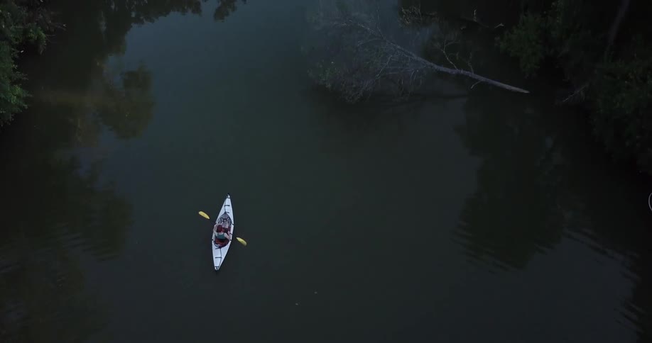 A person paddles a kayak down a stream