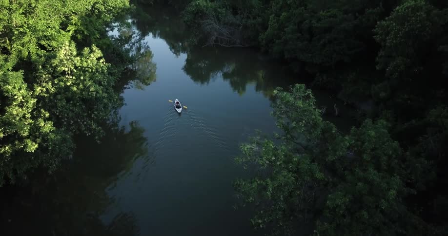 A person paddles a kayak down a stream