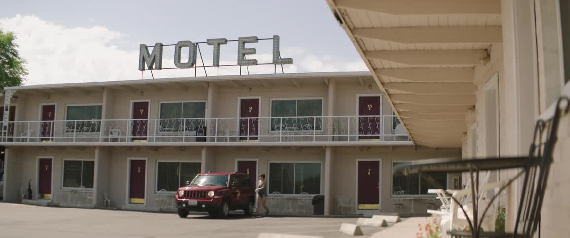 A woman is getting into a car that is parked at a motel