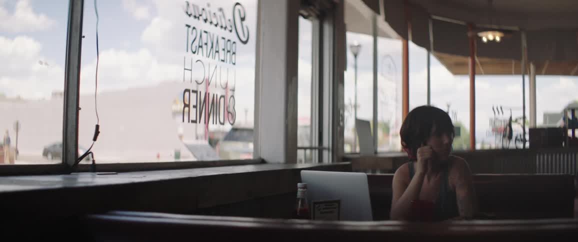 A bored young woman sitting in a booth in a diner