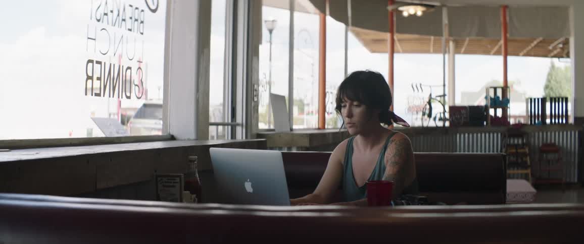 Woman sitting at the table uses laptop in a cafe during daylight