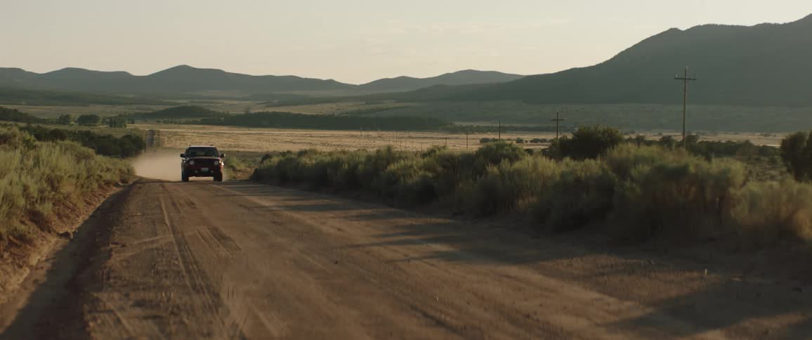 An suv drives down a deserted dirt road near mountains