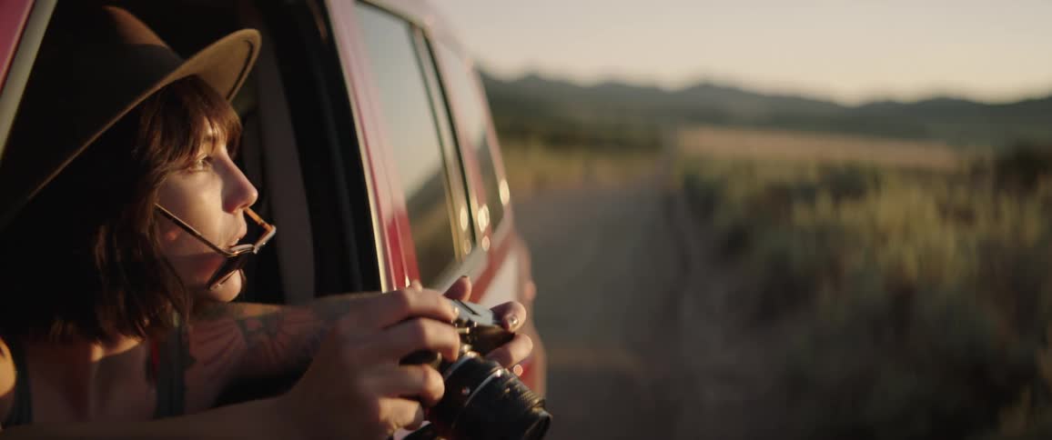 A woman is looking at a camera while sitting in a car
