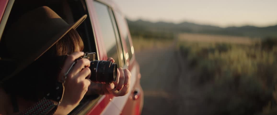 A woman leaning out the window to take a photo with her camera