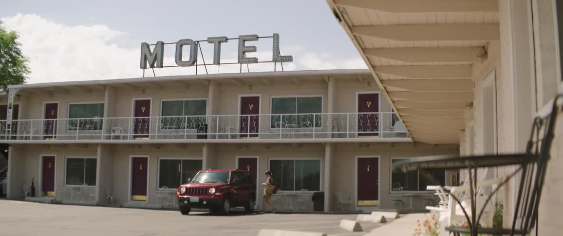 A woman walks out of a motel room and walks to her car