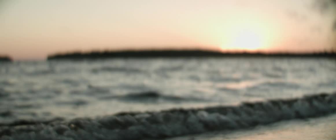 Waves crash onto the shore of a beach at sunrise