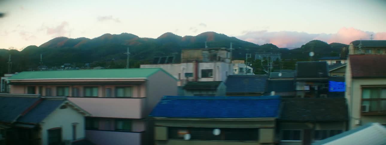 A neighborhood with houses and buildings with trees and a mountain range in the background
