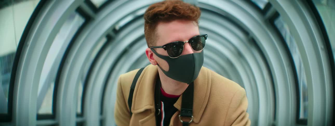 Man wears sunglasses and a face mask in circular glass walled tunnel