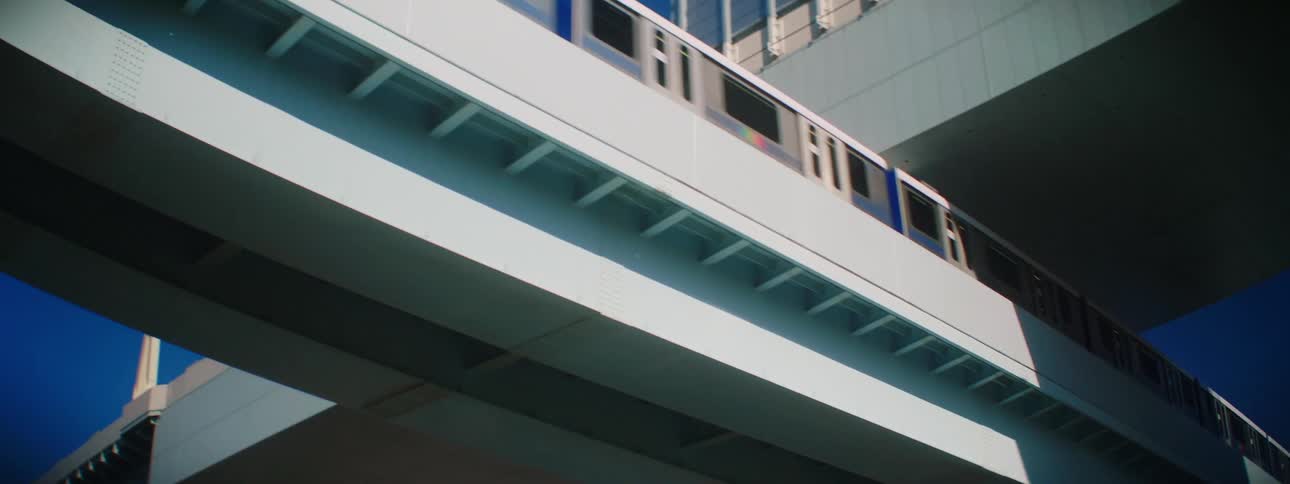 A train with windows running on a track with the sky and clouds above