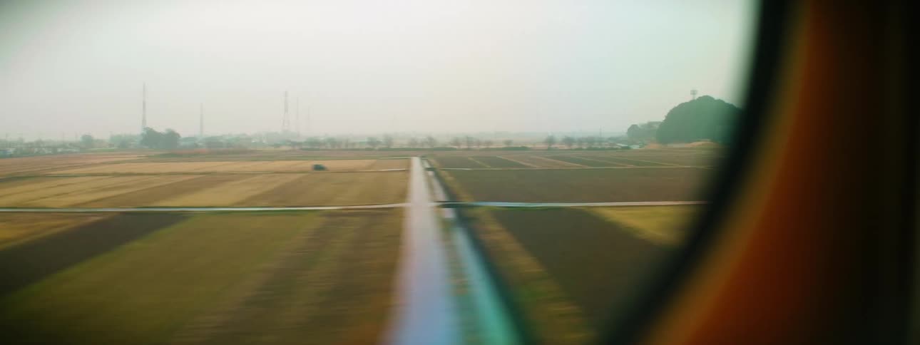 Town and nearby crop fields and waterways flow past window of transport